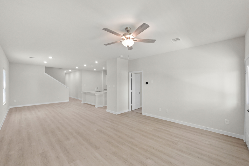 A room with a ceiling fan and a wood floor.