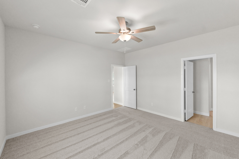 A room with a ceiling fan and a door.