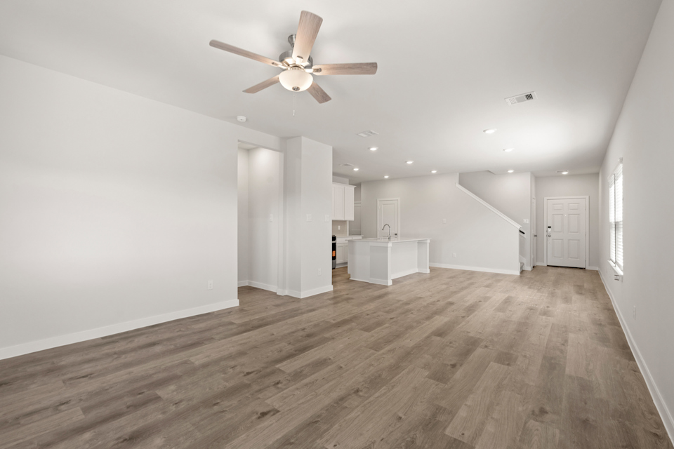 A large empty room with a ceiling fan and a wood floor.