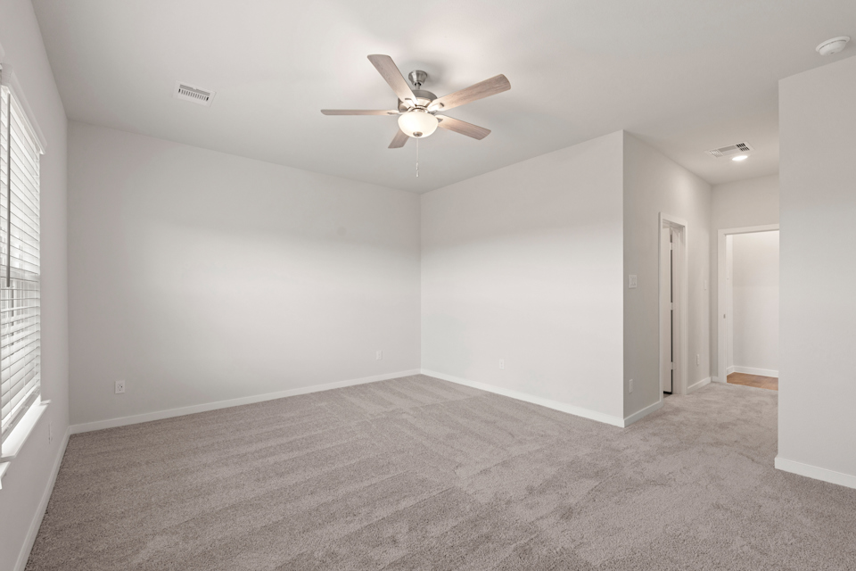 A room with a ceiling fan and a carpet.