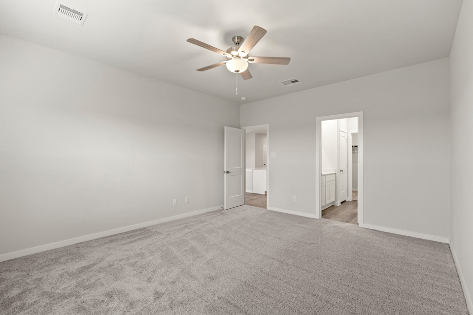 A room with a ceiling fan and a carpet.