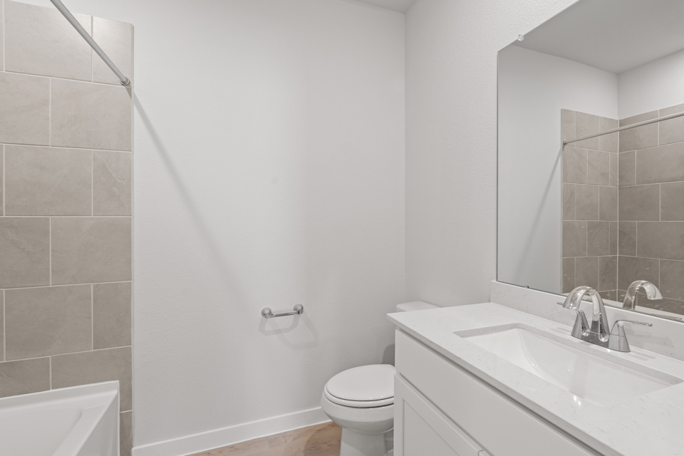 A bathroom with a sink toilet and mirror.