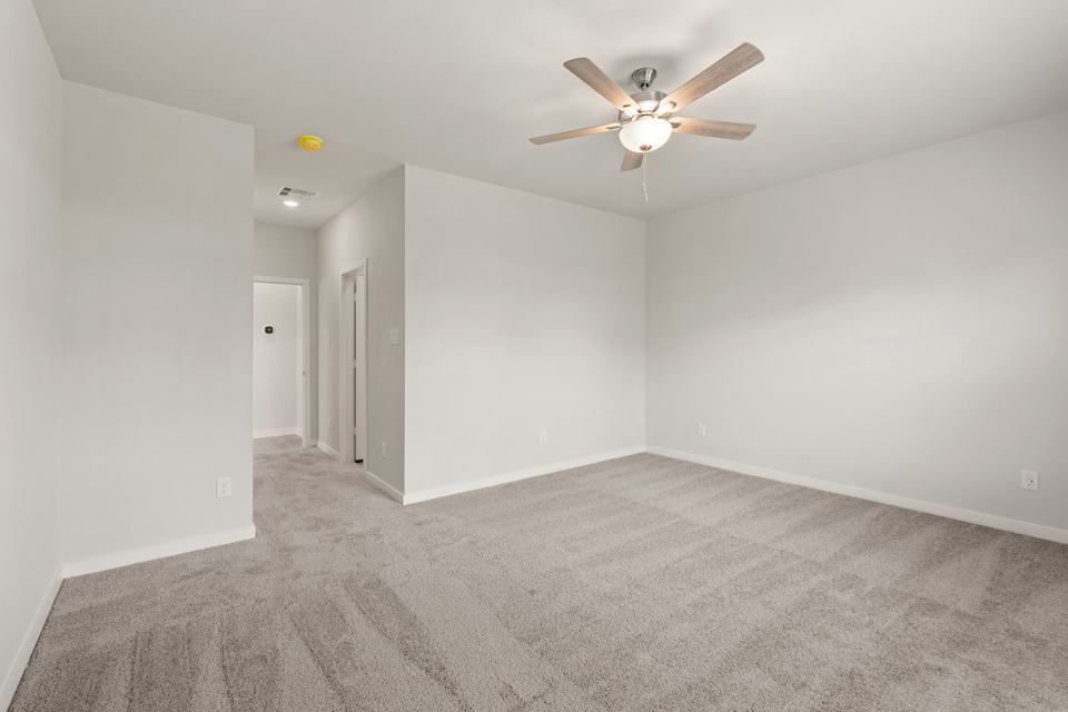A room with a ceiling fan and a carpet.