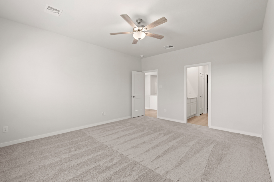 A room with a ceiling fan and a carpet.