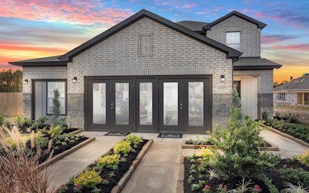 A house with a driveway and a garden in front of it.