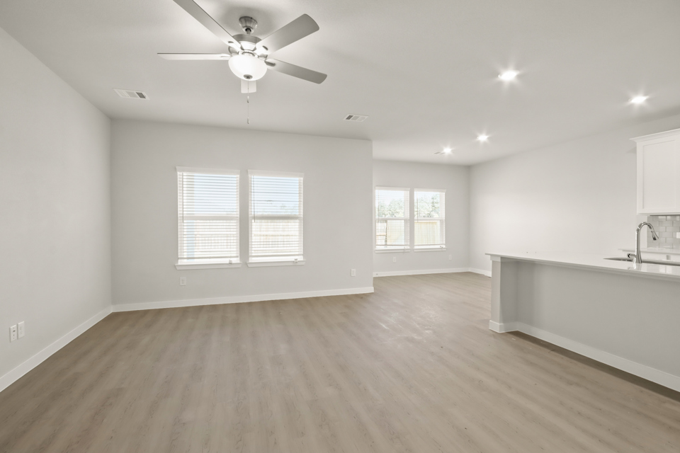 A large empty room with a ceiling fan and a wood floor.