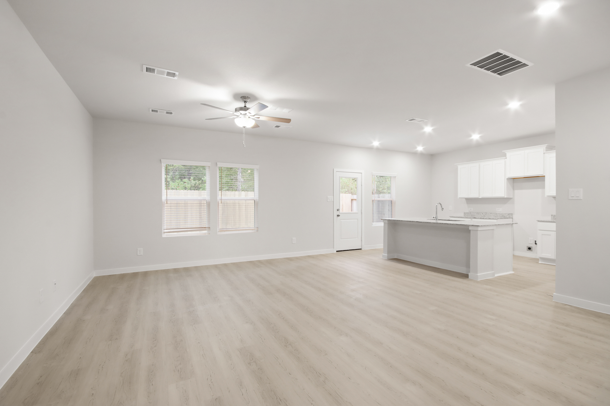 A large empty room with a wood floor and white cabinets.