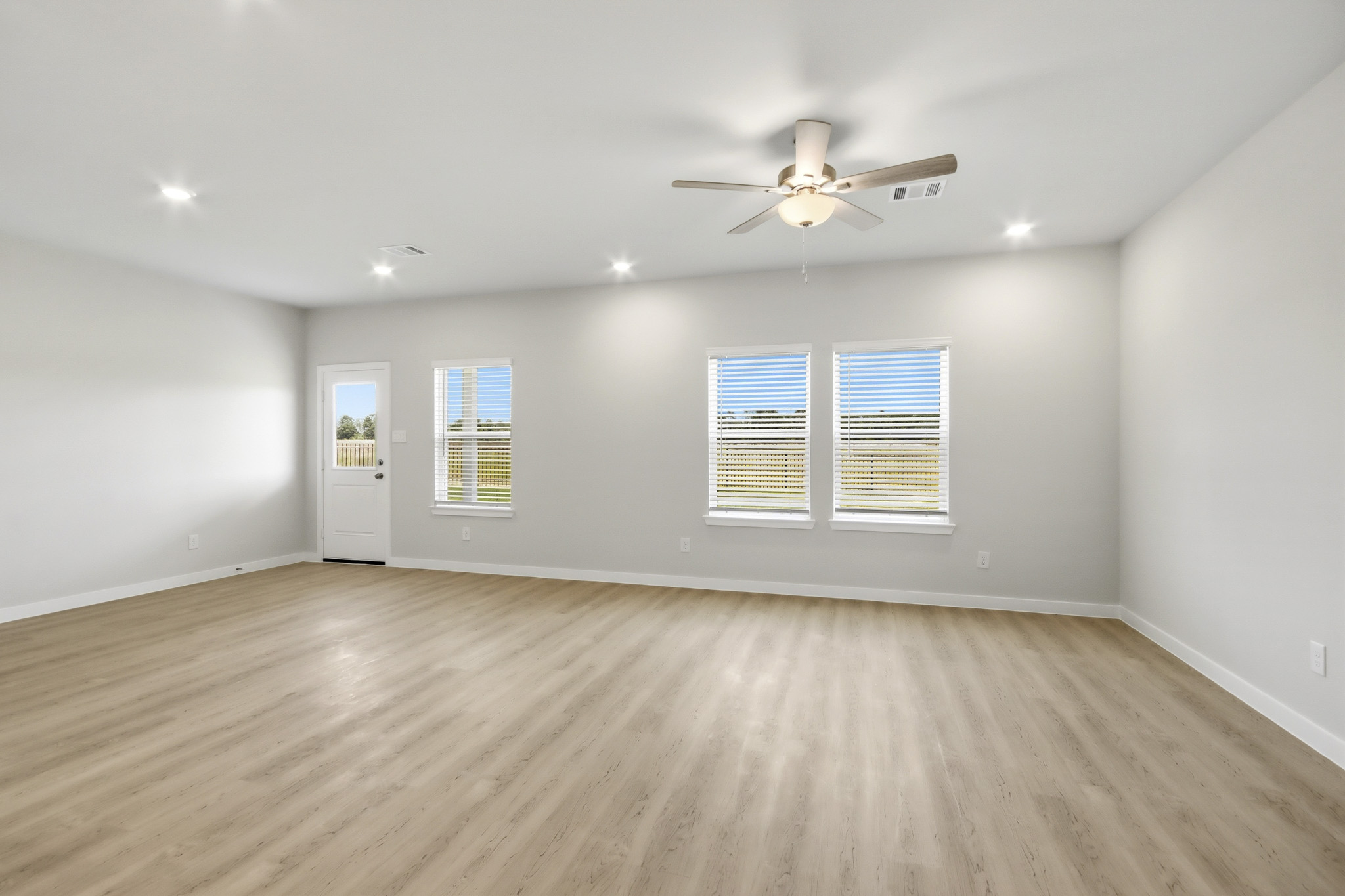 A room with a ceiling fan and a wood floor.