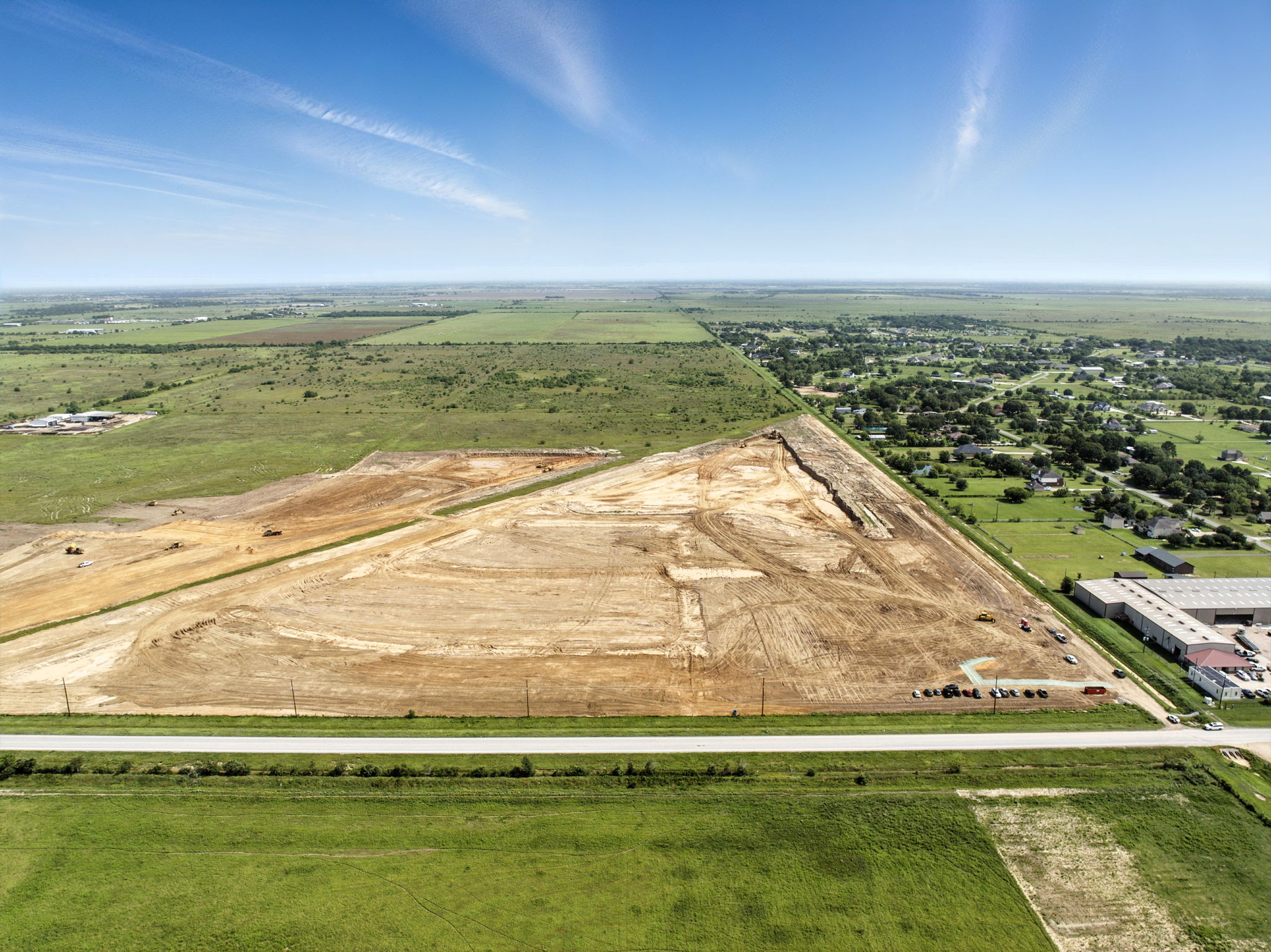 A large field with buildings and trees.