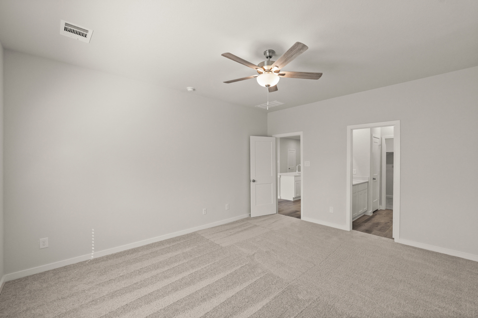 A room with a ceiling fan and a carpet.