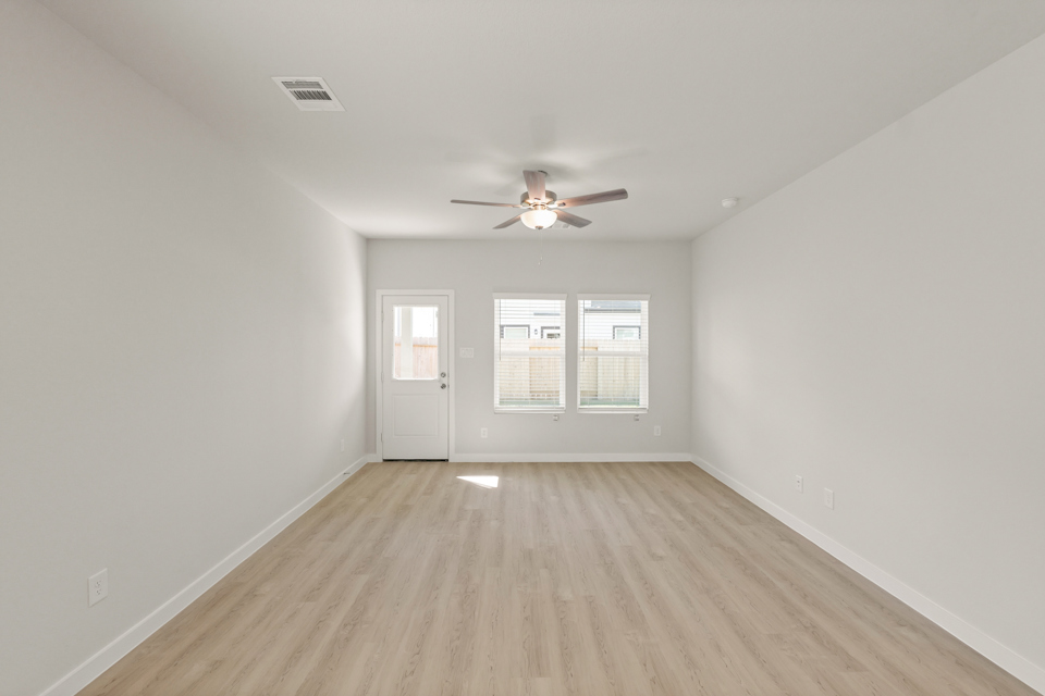 A room with a ceiling fan and a wood floor.