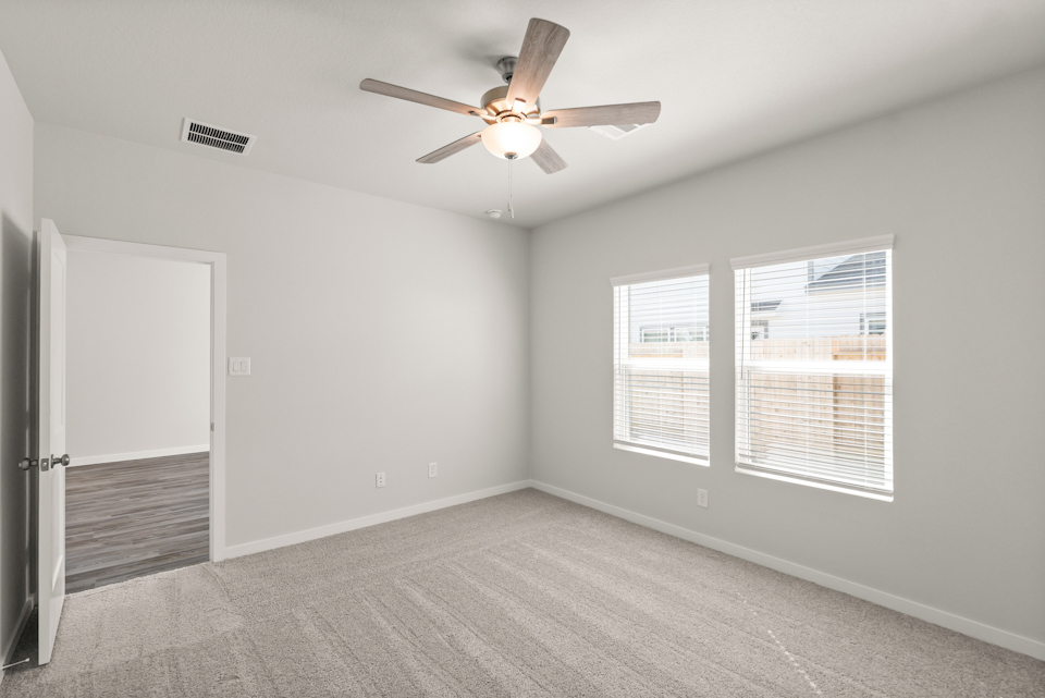 A room with a ceiling fan and a door.