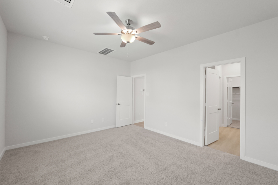 A room with a ceiling fan and a door.