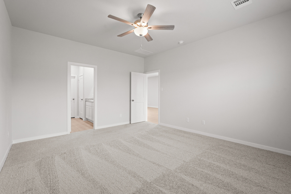 A room with a ceiling fan and a carpet.