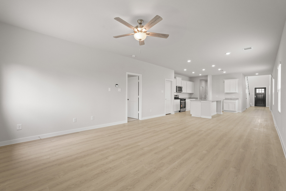A large empty room with a ceiling fan and a wood floor.