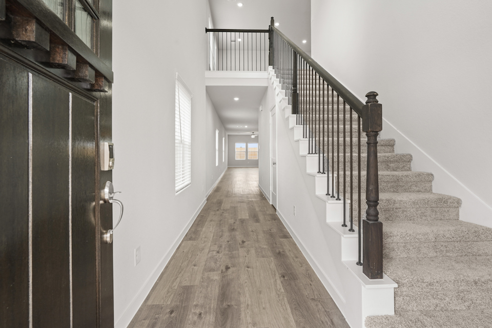 A hallway with a wood floor and white walls.