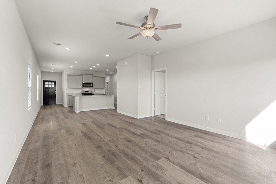 A large empty room with a ceiling fan and a wood floor.