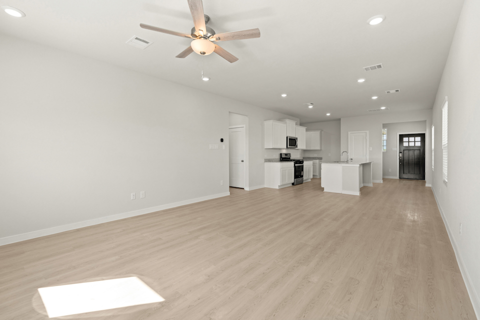 A large empty room with a ceiling fan and a wood floor.