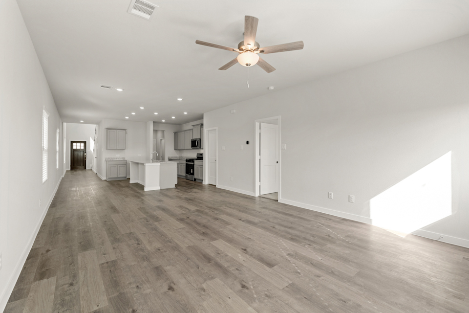 A large empty room with a ceiling fan and a wood floor.