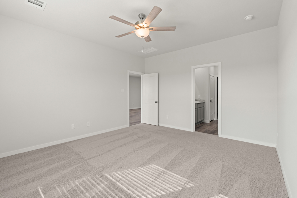 A room with a ceiling fan and a carpet.