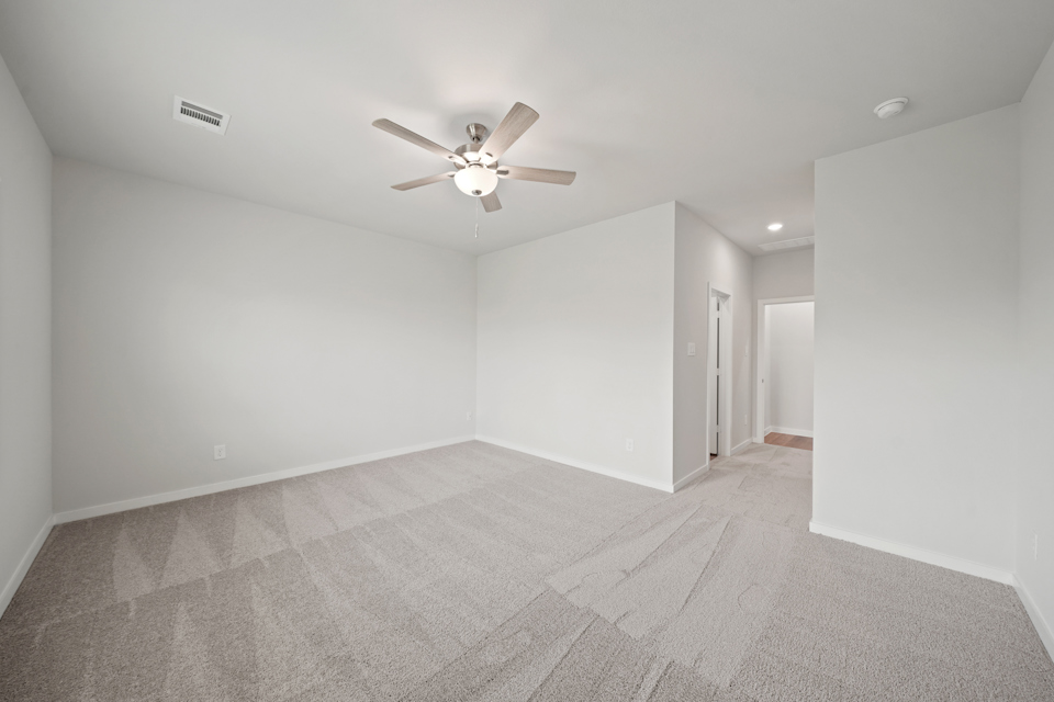 A room with a ceiling fan and a carpet.