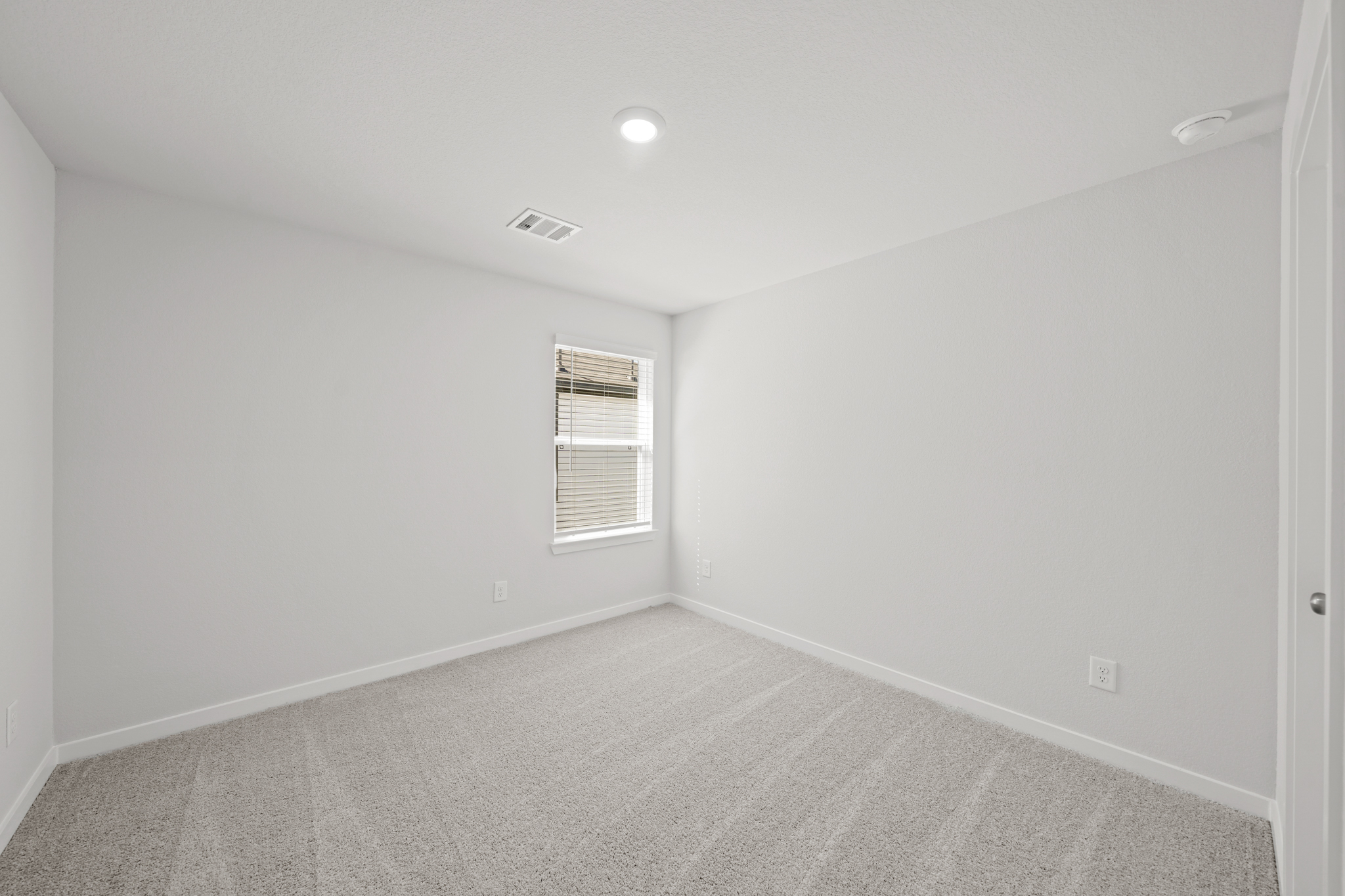 A room with a carpet and a window.