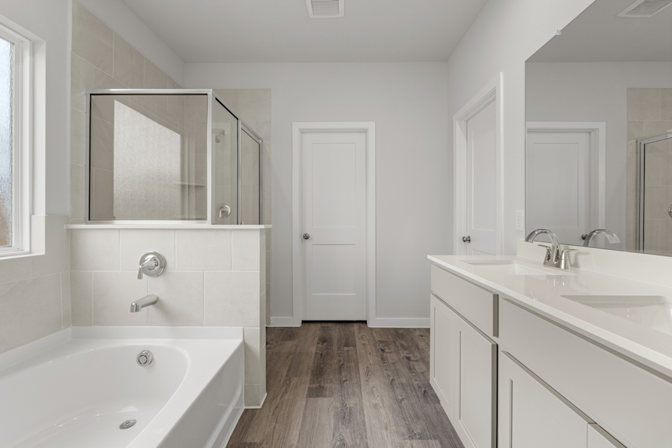 A bathroom with a tub sink and mirror.