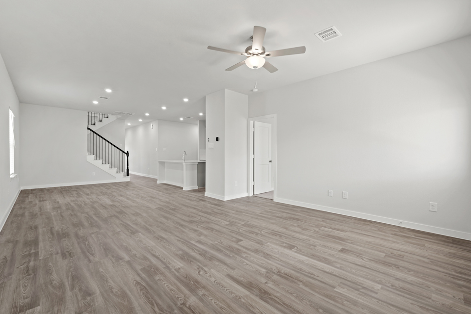 A large empty room with a ceiling fan and a wood floor.
