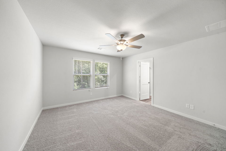 A room with a ceiling fan and a door.