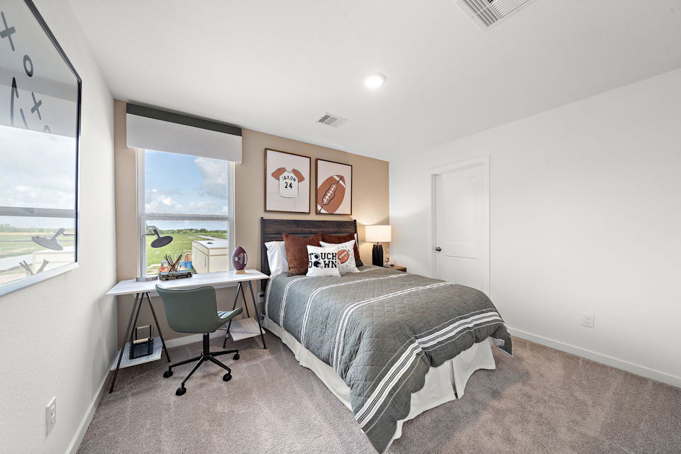 A bedroom with a bed desk and a window.
