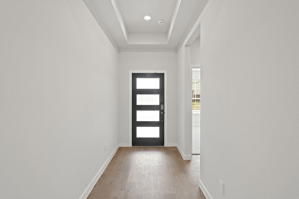 A hallway with a door and windows.