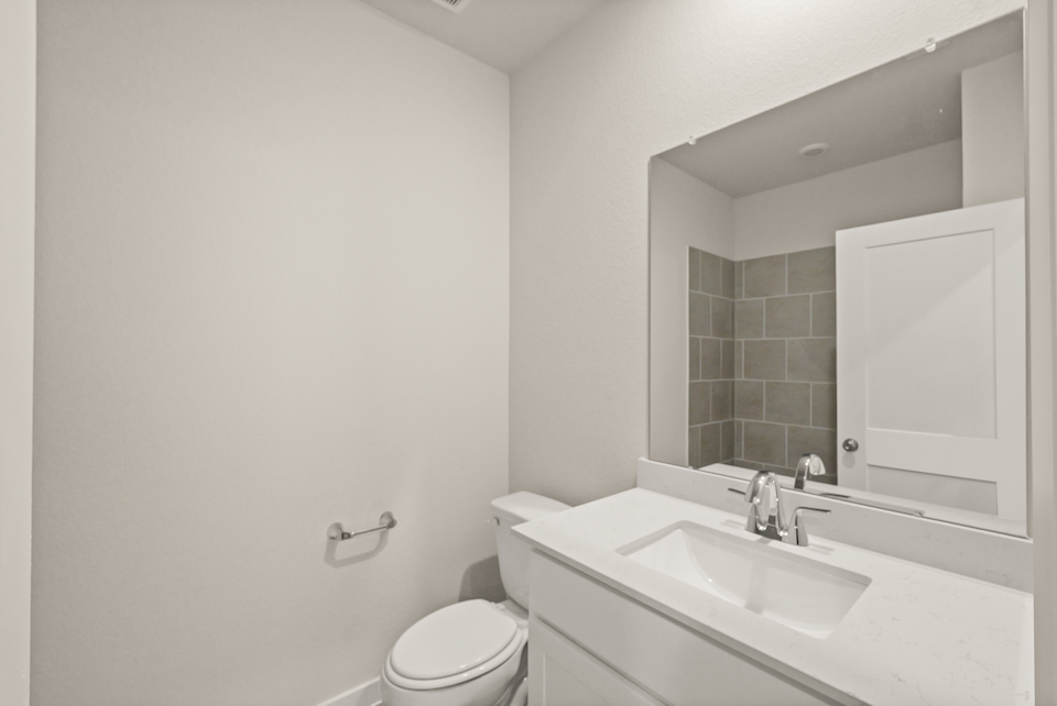 A bathroom with a sink toilet and mirror.