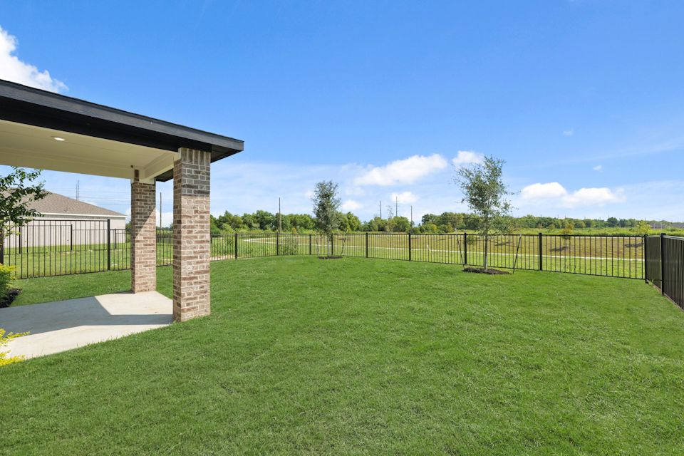 A fenced in yard with a brick structure and a building in the background.