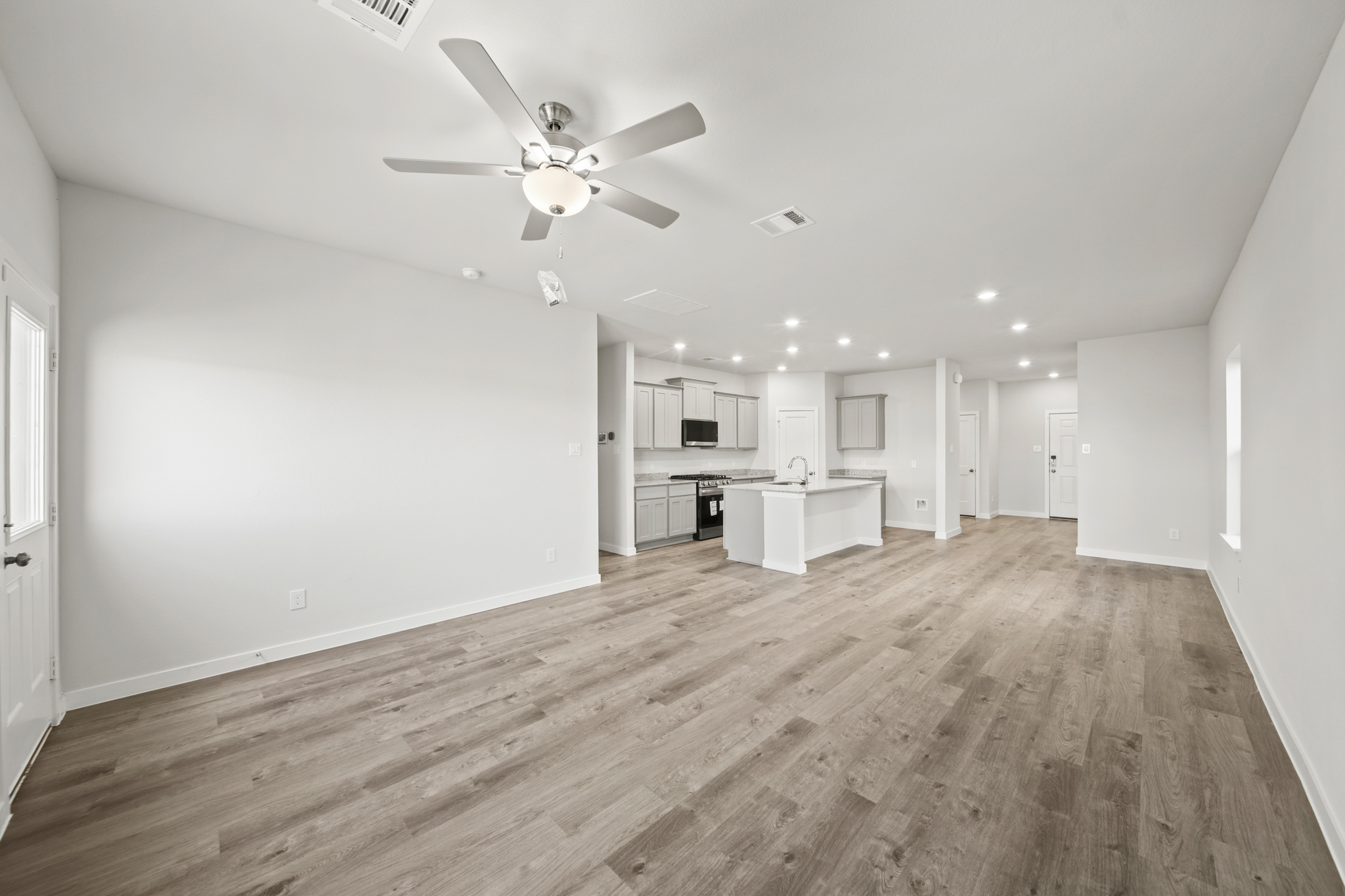 A large empty room with a ceiling fan and a wood floor.