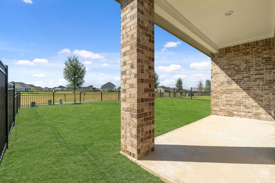 A brick building with a fence and grass.