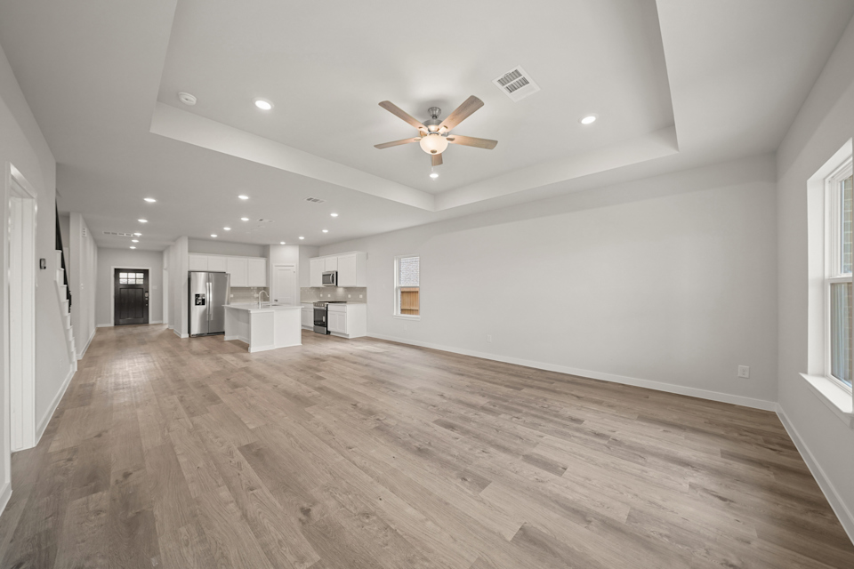 A large empty room with a wood floor and a ceiling fan.