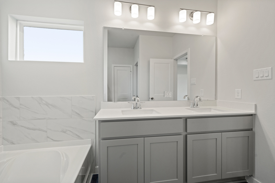 A bathroom with a tub sink and mirror.