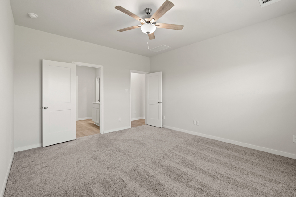 A room with a ceiling fan and white doors.