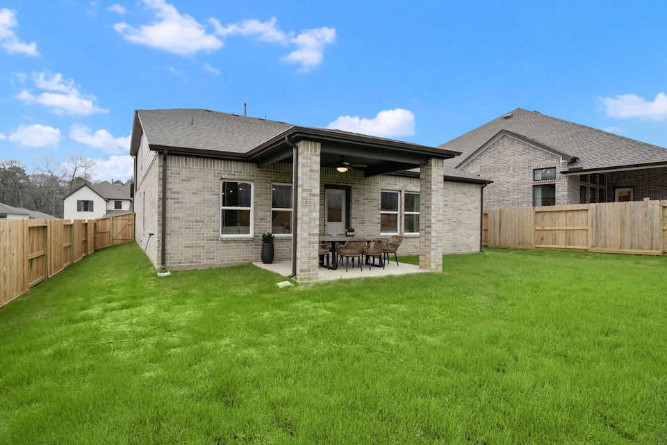 A house with a fence and a lawn in front of it.