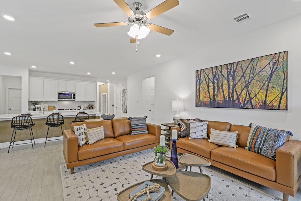 A living room with a couch and a fan.