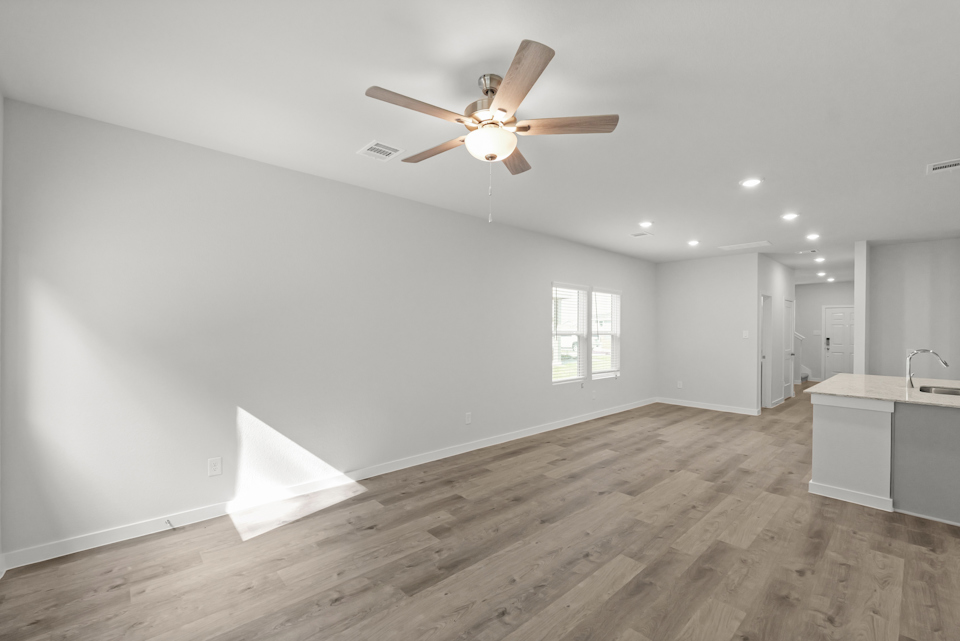 A room with a ceiling fan and a wood floor.