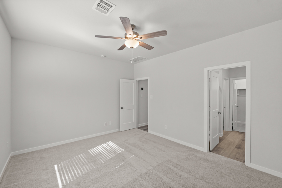 A room with a ceiling fan and white walls.