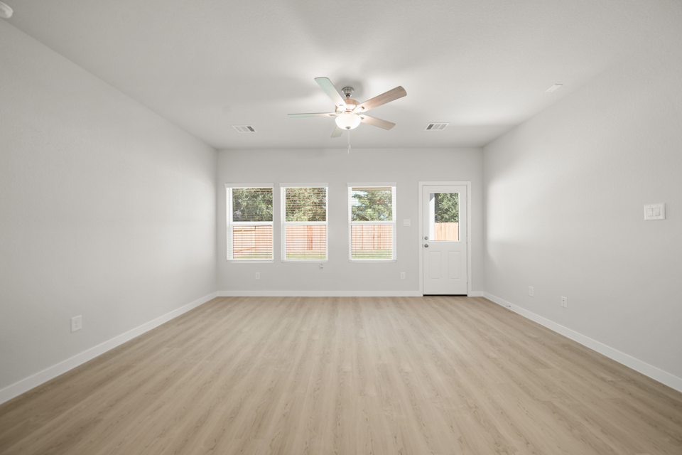 A room with a ceiling fan and a wood floor.