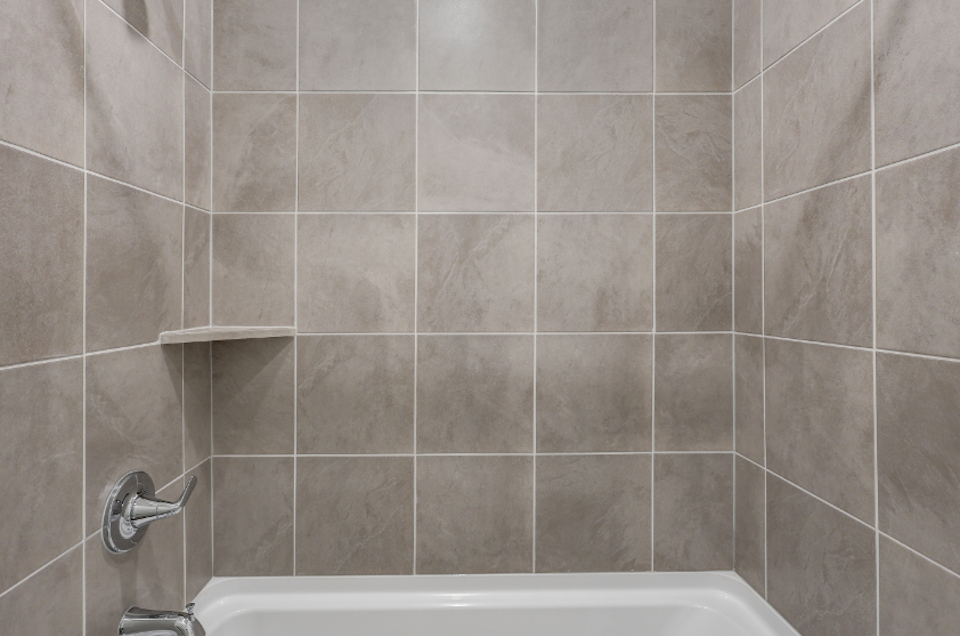 A bathtub with a tile wall.