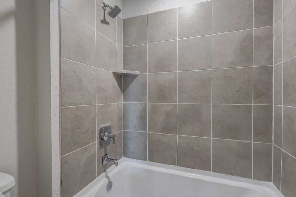 A bathtub with a tile wall.