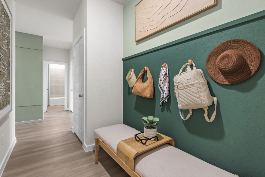 A room with a bench and a hat on the wall.