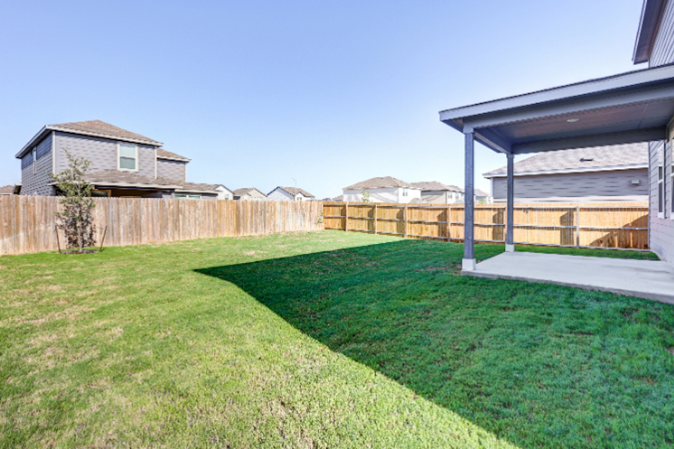 A backyard with a fence and grass.