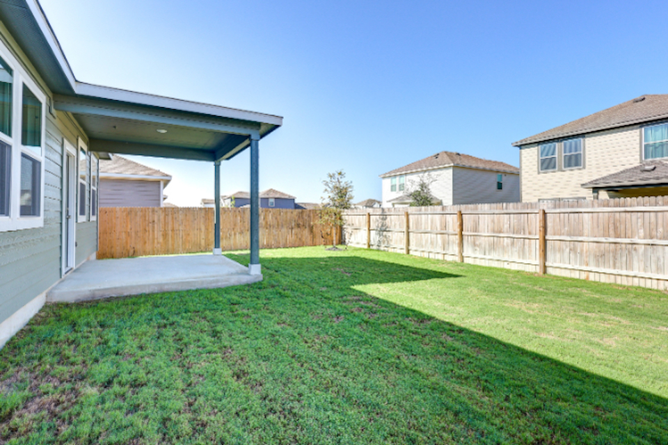 A backyard with a fence and grass.