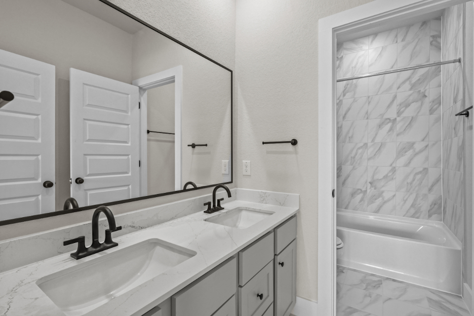 A bathroom with a tub sink and mirror.