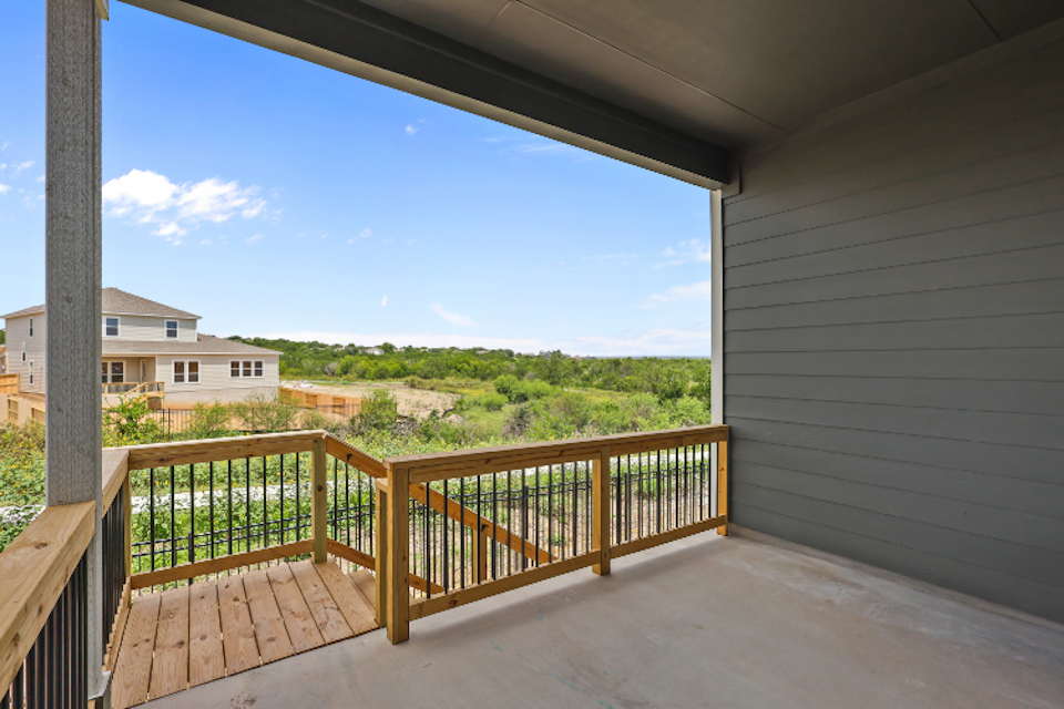 A deck with a railing and a building in the background.